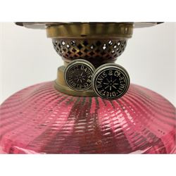 Victorian table standing oil lamp, brass fittings, cranberry glass reservoir, brass column on black enamelled ceramic base, with a frosted glass shade and clear glass chimney, H68cm