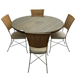Contemporary teak and metalwork conservatory table, circular plank top with removable glass surface over metal quadriform base (W120cm H75cm); and matching set of four chairs, rattan back over cream upholstered seats, on metalwork base (W40cm H878cm)