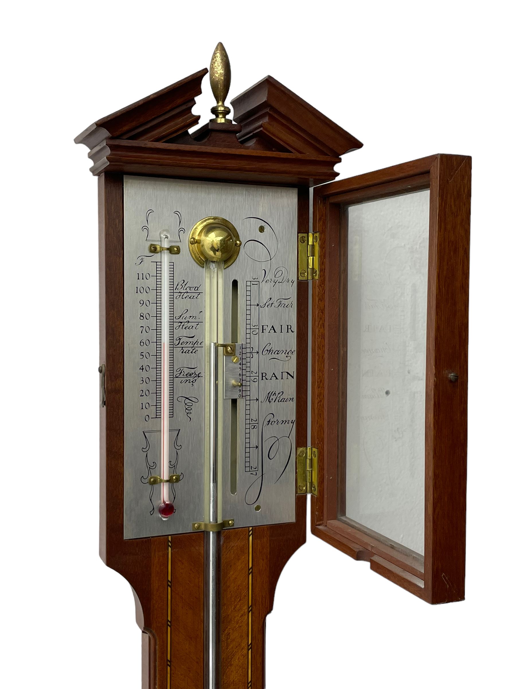 20th century - mercury cistern barometer in an 18th century style mahogany case with contrasting inlay and a broken pediment, round base with a turned cistern cover, fully exposed glass tube and silvered register within a glazed door, with a Fahrenheit spirit thermometer, engraved weather predictions and sliding vernier. Mercury clean and present.
