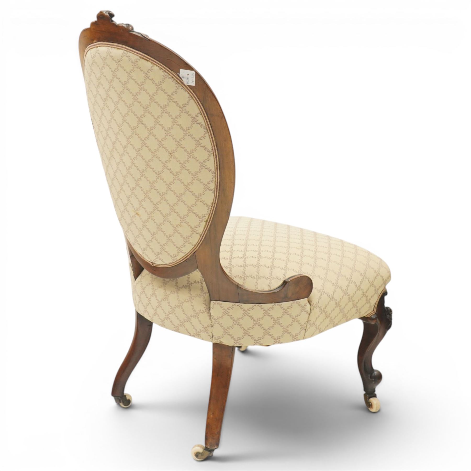 Pair of Victorian walnut framed ladies salon nursing chairs, oval cameo back with carved cartouche carved cresting rail, sprung seat upholstered in foliate patterned ivory fabric, shaped apron carved with scroll and cartouche decoration, on cabriole supports with moulded flower knees, retailed by David Hick Interiors, Jersey