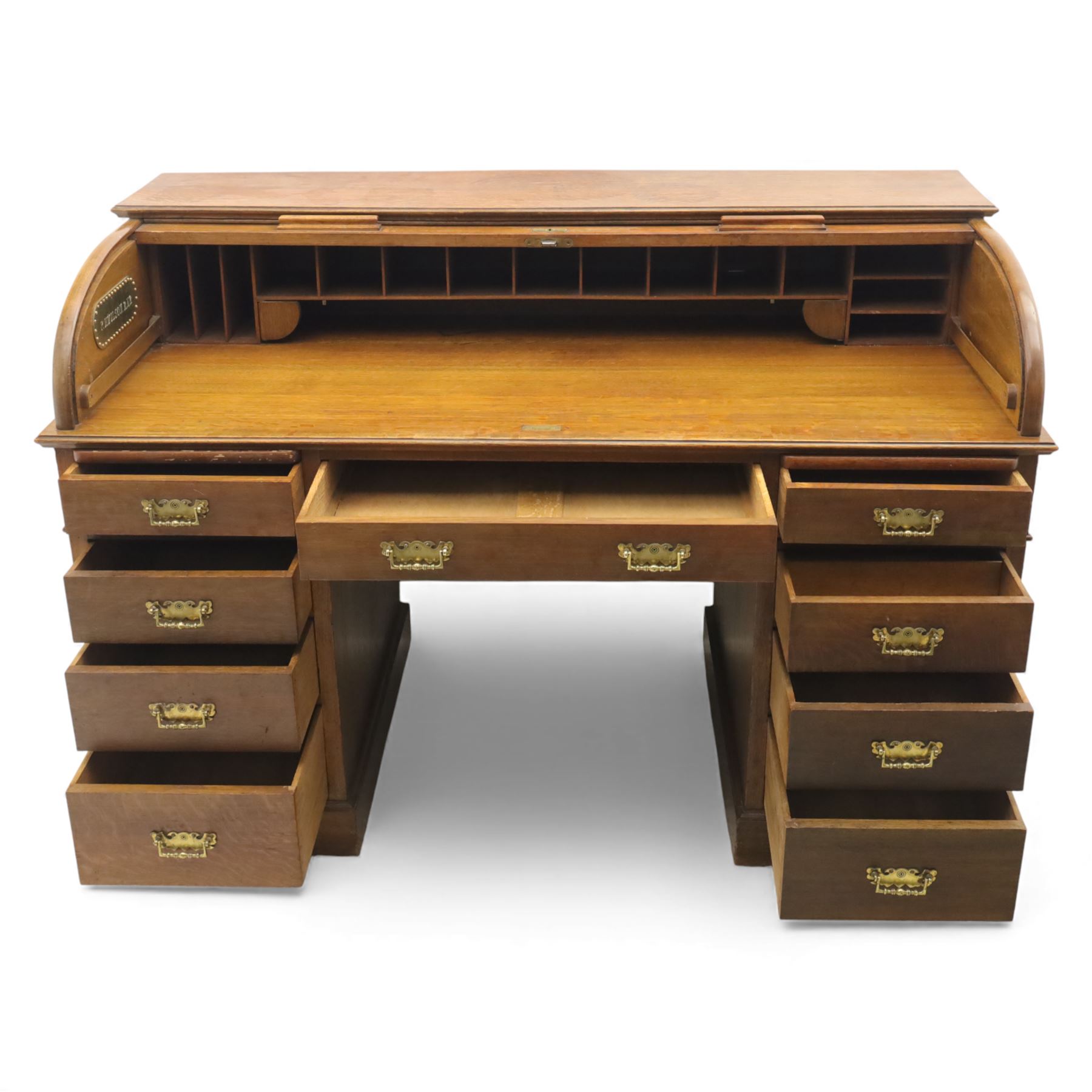 Edwardian oak roll-top desk, the tambour enclosing a fitted interior of pigeonholes and dividers, over a central kneehole flanked by twin banks of drawers with brass handles, on plinth bases