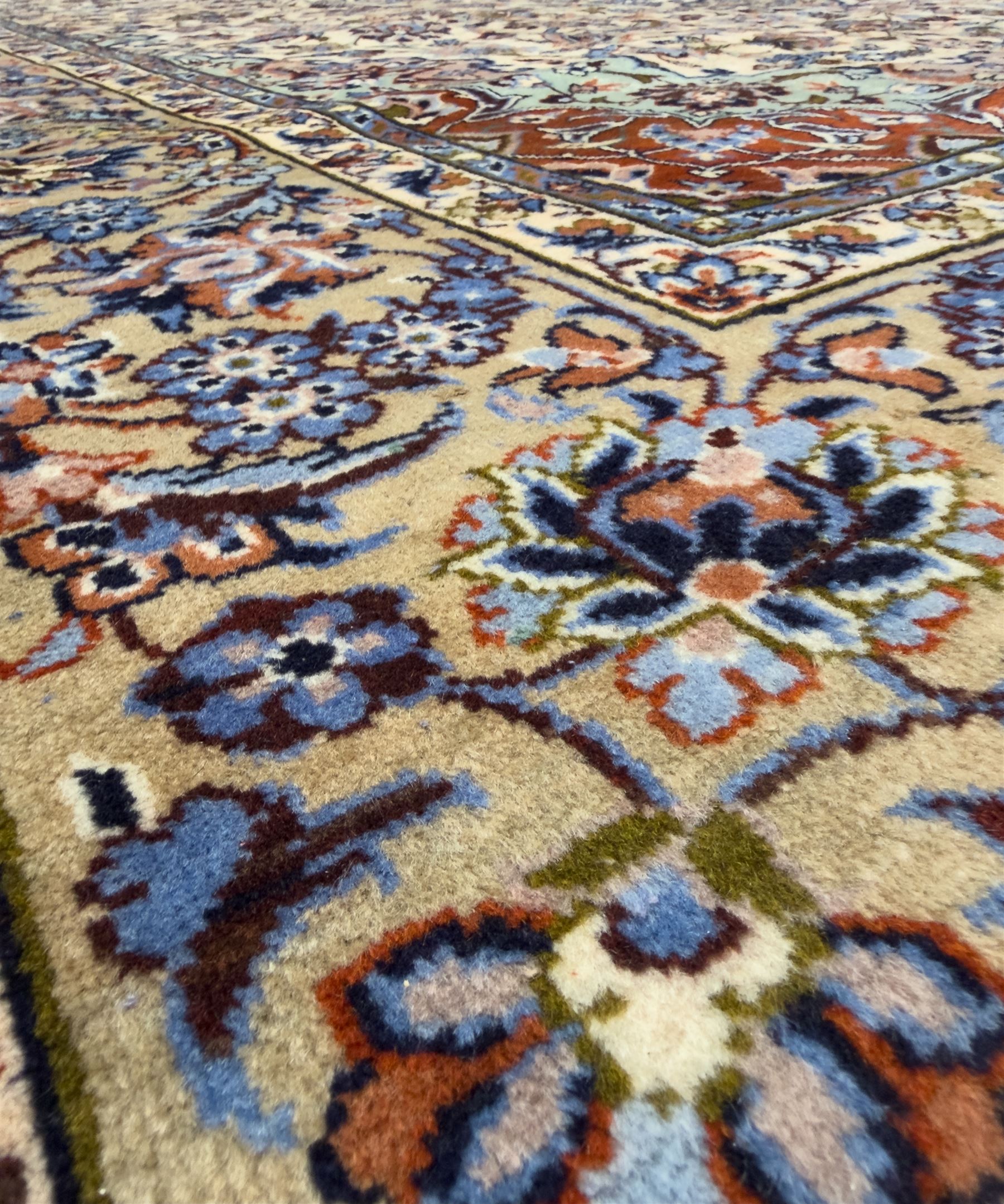Central Persian Najafabad hand-knotted carpet, the ivory field with a central floral medallion radiating palmettes and arabesques in tones of blue, lilac and tan, enclosed by a wide navy border of scrolling vine and rosette motifs, with red spandrels and multiple guard stripes