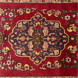 North West Persian Tariz hand-knotted runner, madder red field with a column of linked lozenge medallions in shades of indigo blue and pistachio green framed by stylized floral motifs within triple borders of rosettes and scrolling vines on an ivory ground, with cotton fringe ends