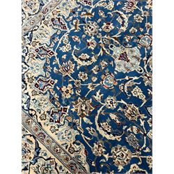 Persian Kashan blue ground rug, central floral rosette medallion within a field of swirling branches and palmettes, the border with trailing pattern interspersed with stylised plant motifs