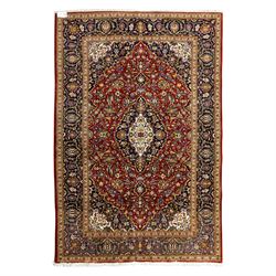 Central Persian Kashan hand-knotted carpet, crimson ground, with a central ivory shaped fl...