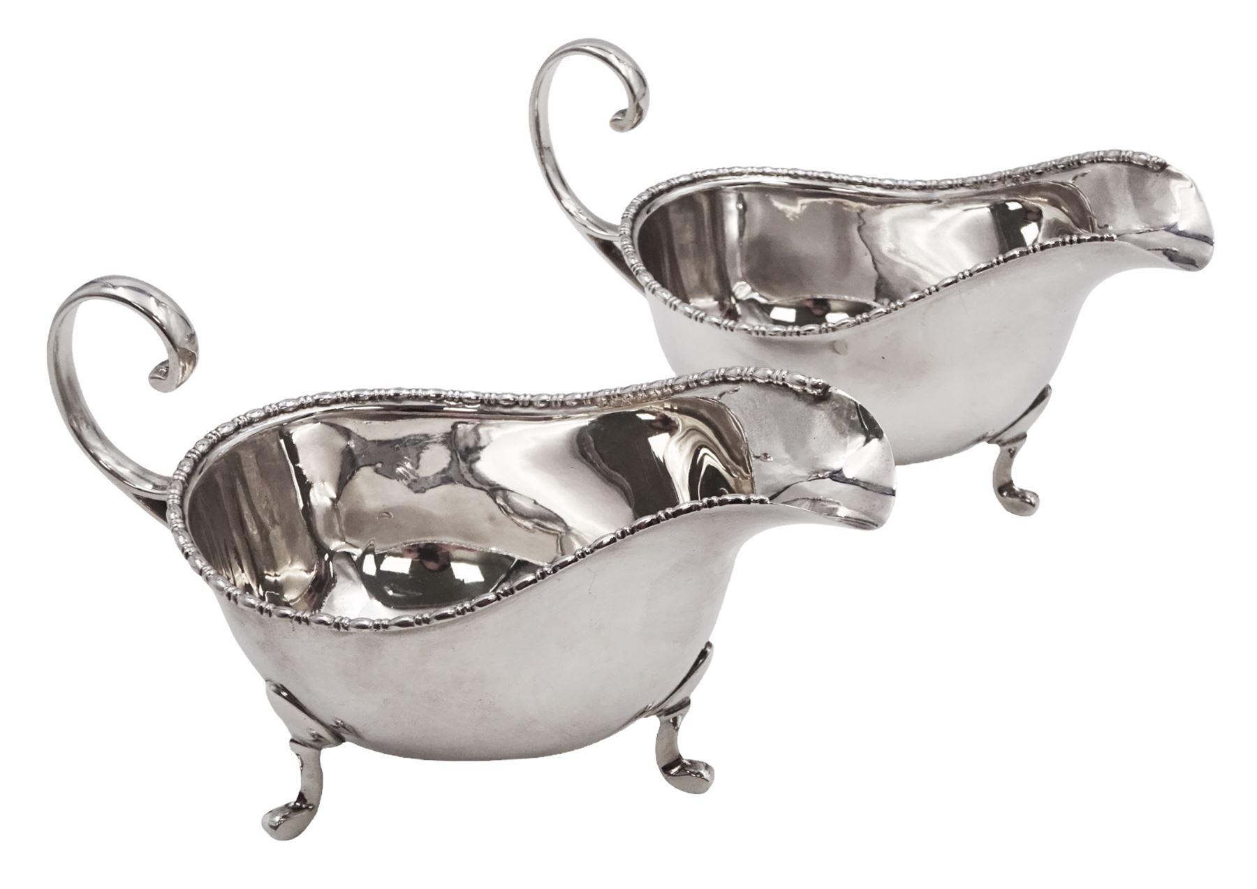 Pair of 1930s silver sauce boats, of typical plain form, each with bead and dart rim and flying scroll handles, upon three pad feet, hallmarked Walker & Hall, Birmingham 1935
