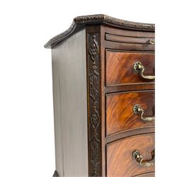 Chippendale design serpentine chest, shaped moulded top carved with repeating flower head motifs, fitted with brushing slide over four graduating drawers, pierced and foliate moulded handle plates with scrolled swan neck handles, canted upright corners carved with flower heads and strapwork, on canted ogee bracket feet