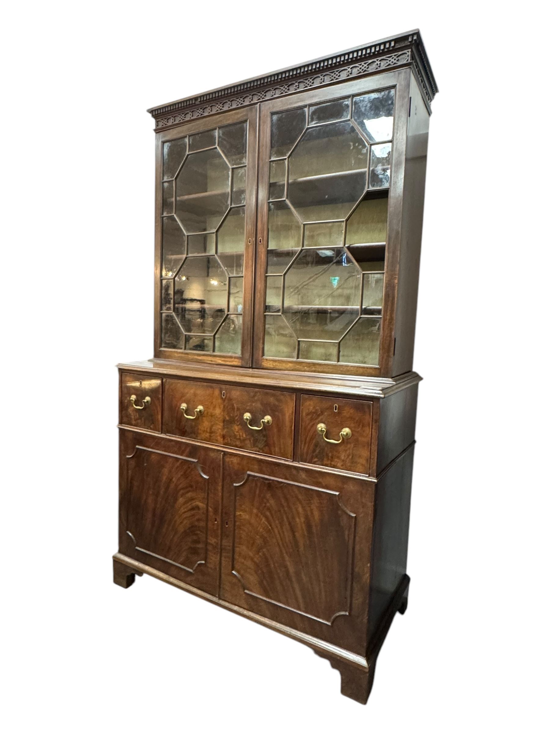 George III mahogany bookcase secretaire, dentil cornice over blind fret work frieze, enclosed by two astragal glazed doors, central secretaire drawer with fall front enclosing leather writing surface and small drawers, two flanking short drawers over double cupboard, on bracket feet