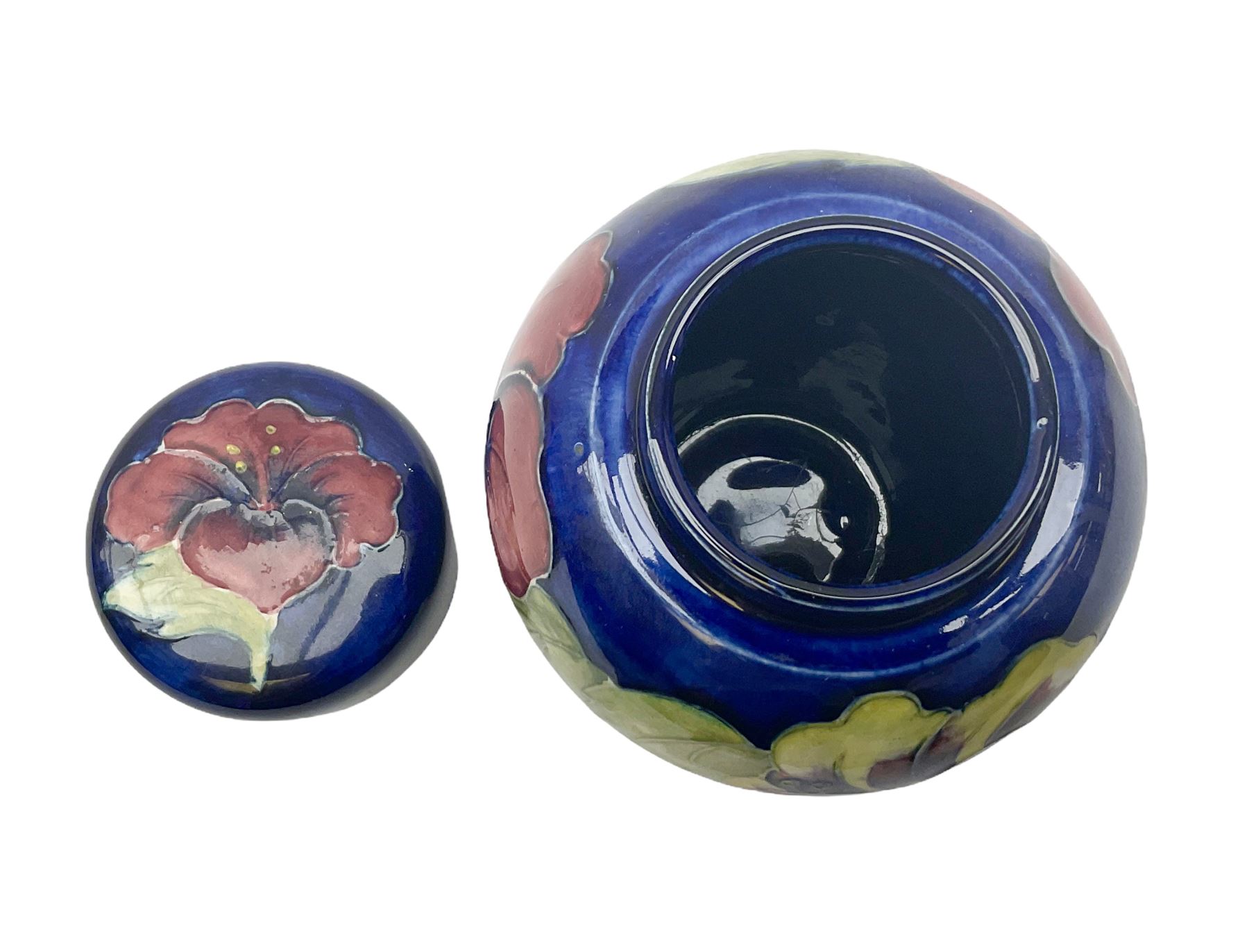 Moorcroft ginger jar, decorated in the Hibiscus pattern upon a blue ground, with paper label beneath detailed 'Potters to the late Queen Mary', H11cm.