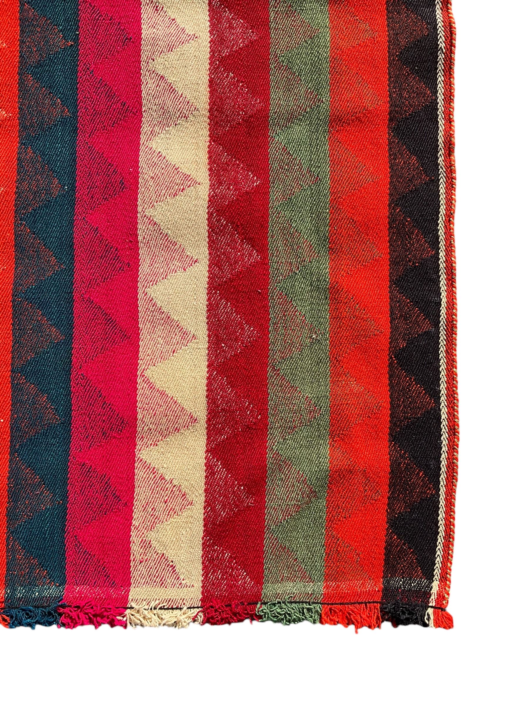Southwest Persian Jajim Kilim ground rug, decorated with alternating vertical stripes in shades of crimson, orange, green, and black, with subtle triangular motifs woven into each stripe, bordered by narrow bands