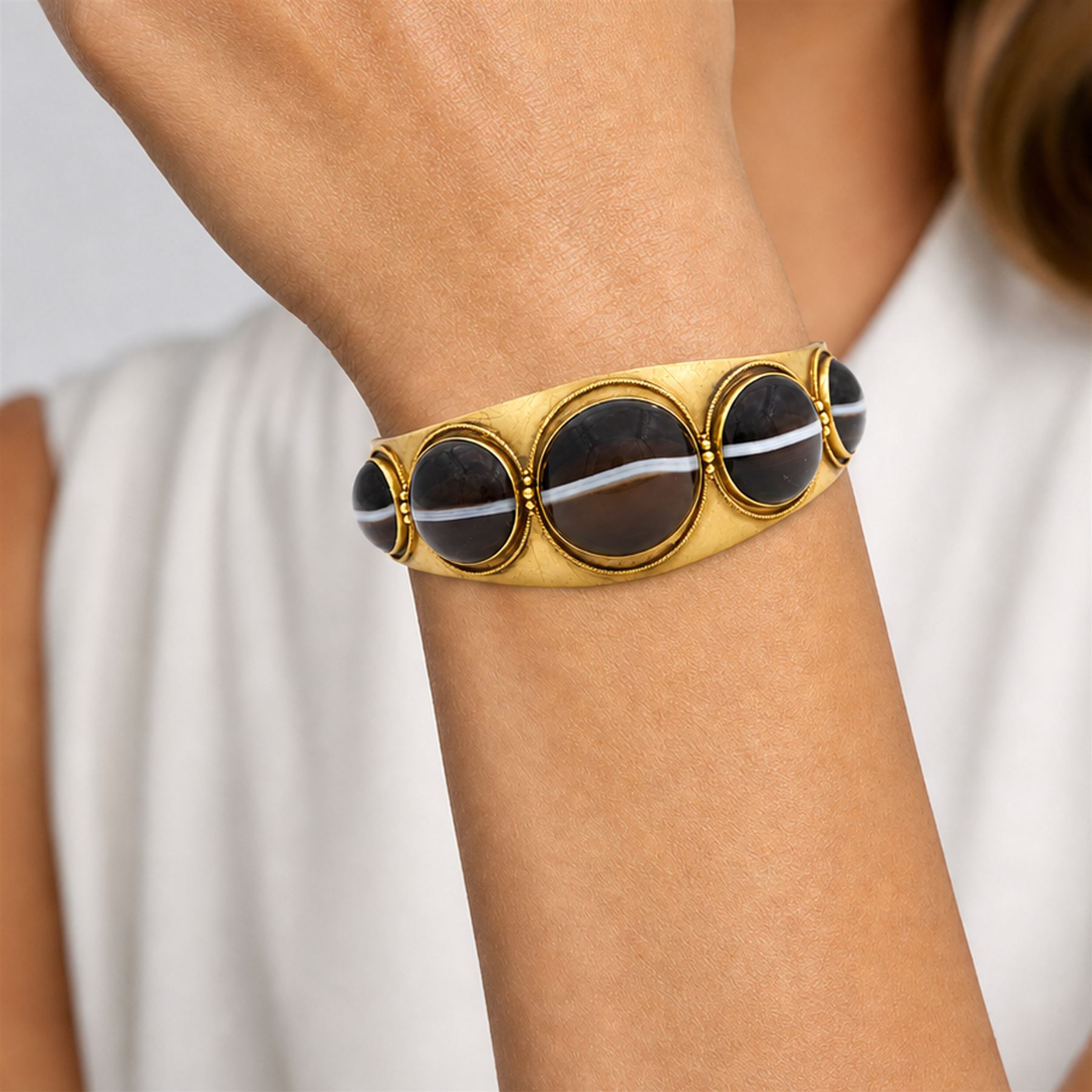 Victorian gold banded agate hinged bangle, set with five graduating cabochon cut agates, surrounded by wirework and bead decoration
