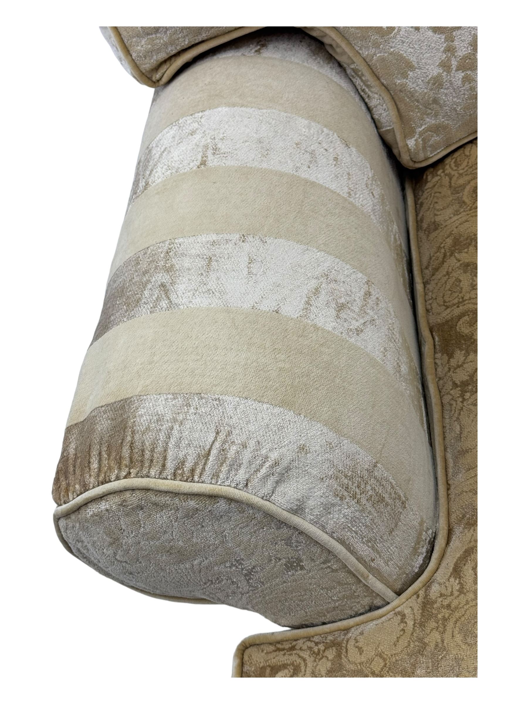 Contemporary two-seat sofa, upholstered in damask fabric with a pale gold floral pattern, rolled arms with covers, loose back and seat cushions, on matching skirted base with concealed castors