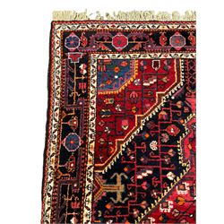 Persian Hamadan red and indigo ground rug, central lozenge medallion with extending poles, the field decorated with interlaced branches and flowerheads, guarded border with stylised floral motifs