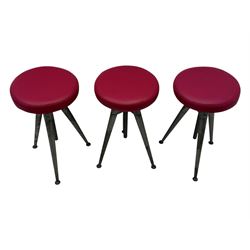 Contemporary industrial design riveted metal table, by repute fashioned from salvaged aeroplane parts, with a circular glass top on a tripod base, accompanied by three adjustable stools upholstered in burgundy