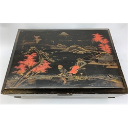  A 20th century Chinese black lacquer and gilt detailed writing box, decorated with figures, pagodas and cranes amidst a mountainous landscape, the hinged cover opening to reveal a compartmented interior and fold out baize lined slope, H20cm L46.5cm D31.5cm.   