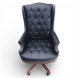 Chesterfield style desk chair upholstered in black, brass studded trim with tall button backed seat, with faux wooden base raised upon castors