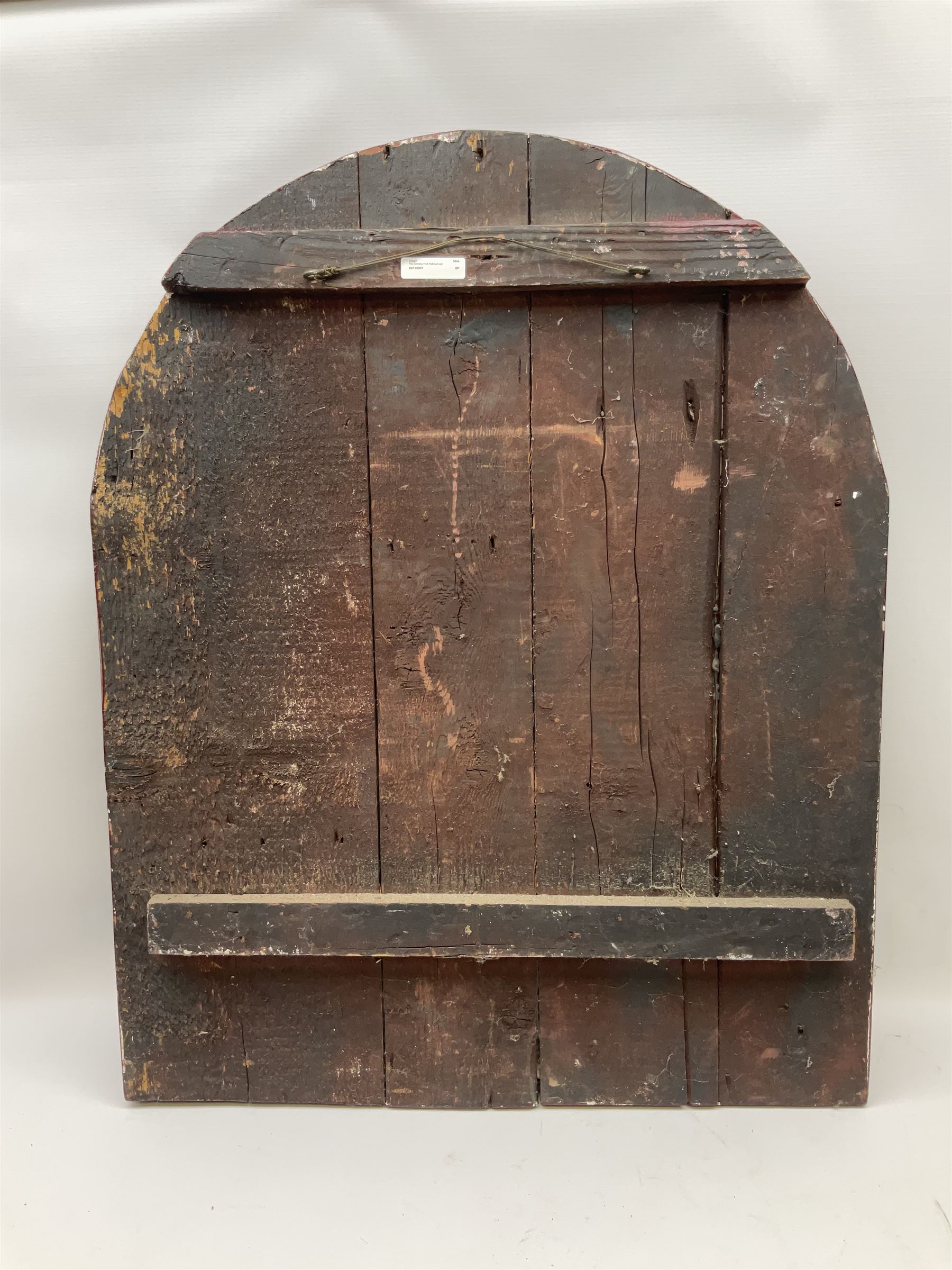 `The Grimsby-York Railroad Co.` painted wooden railway advertising sign 20th century, of planked construction with arched top and moulded border, decorated with an applied wood and metal image of an early steam locomotive in relief, the surrounding wording reading `The Grimsby-York Railroad Co., Fast Dispatch by Rail from Fish Curing Houses of Grimsby & Hull, Est. 1873, Daily Connections to Billingsgate`, 89 x 71cm
