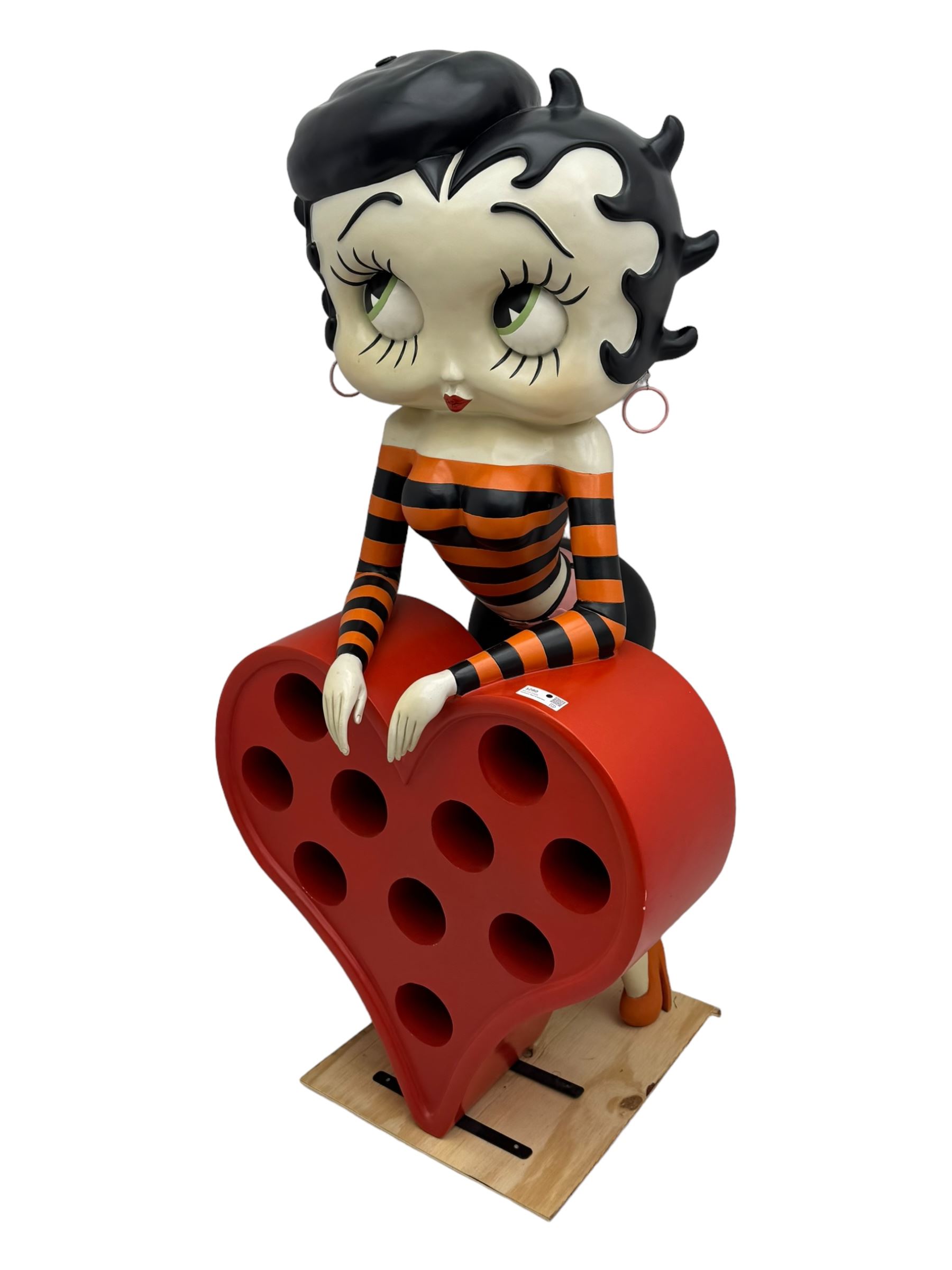 Contemporary large-scale Betty Boop painted wine rack, modelled leaning against a heart-shaped stand with ten circular bottle slots, dressed in black and orange striped attire