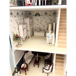 Georgian style wooden double fronted three-storey dolls house with pale blue stucco finish under a faux tiled roof with two chimney stacks, the double hinged front opening to reveal six fully decorated rooms with floor coverings, central staircase, porcelain fitted bathroom, kitchen with deep white sink and Aga cooker, electric lighting with adaptor, fully furnished with French style and other furniture, grand piano etc, and comprehensive range of accessories H82cm W61cm D31cm