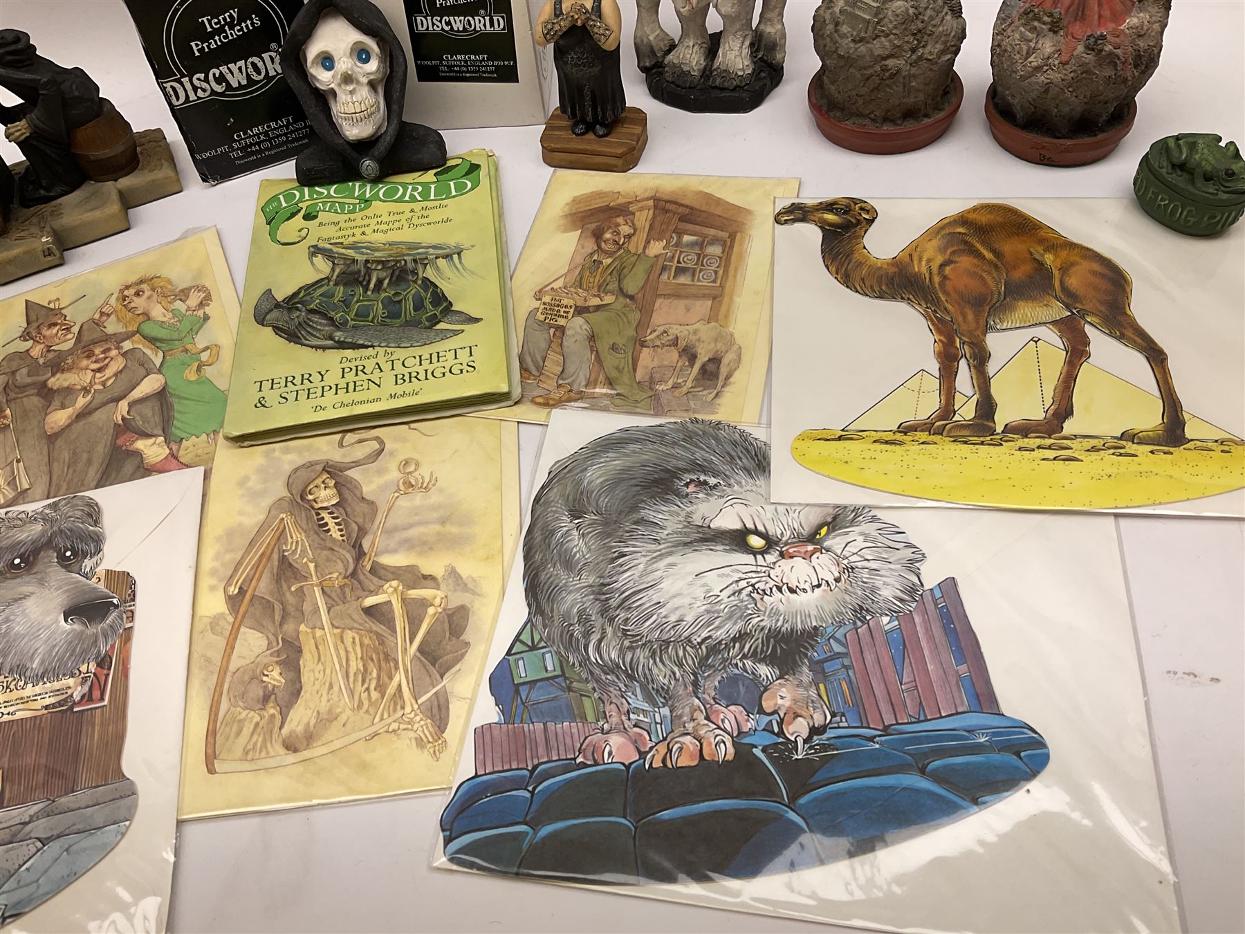 Terry Pratchett Discworld figures, designed by Clarecraft, comprising Death and Granny Weatherwax, DW90, Deathhead DWE8, Dried-frog pill box, boxed, DW63, Death as Beau Nidle, boxed, DW88, Agnes Nitt DW68, Detritus, DW22, Bonsai mountain, DW78, Volcanic bonsai mountain, boxed, DW79, Bonsai mountain valley, DW80, together with the Discworld mapp, and a collection of Terry Pratchett cards.  