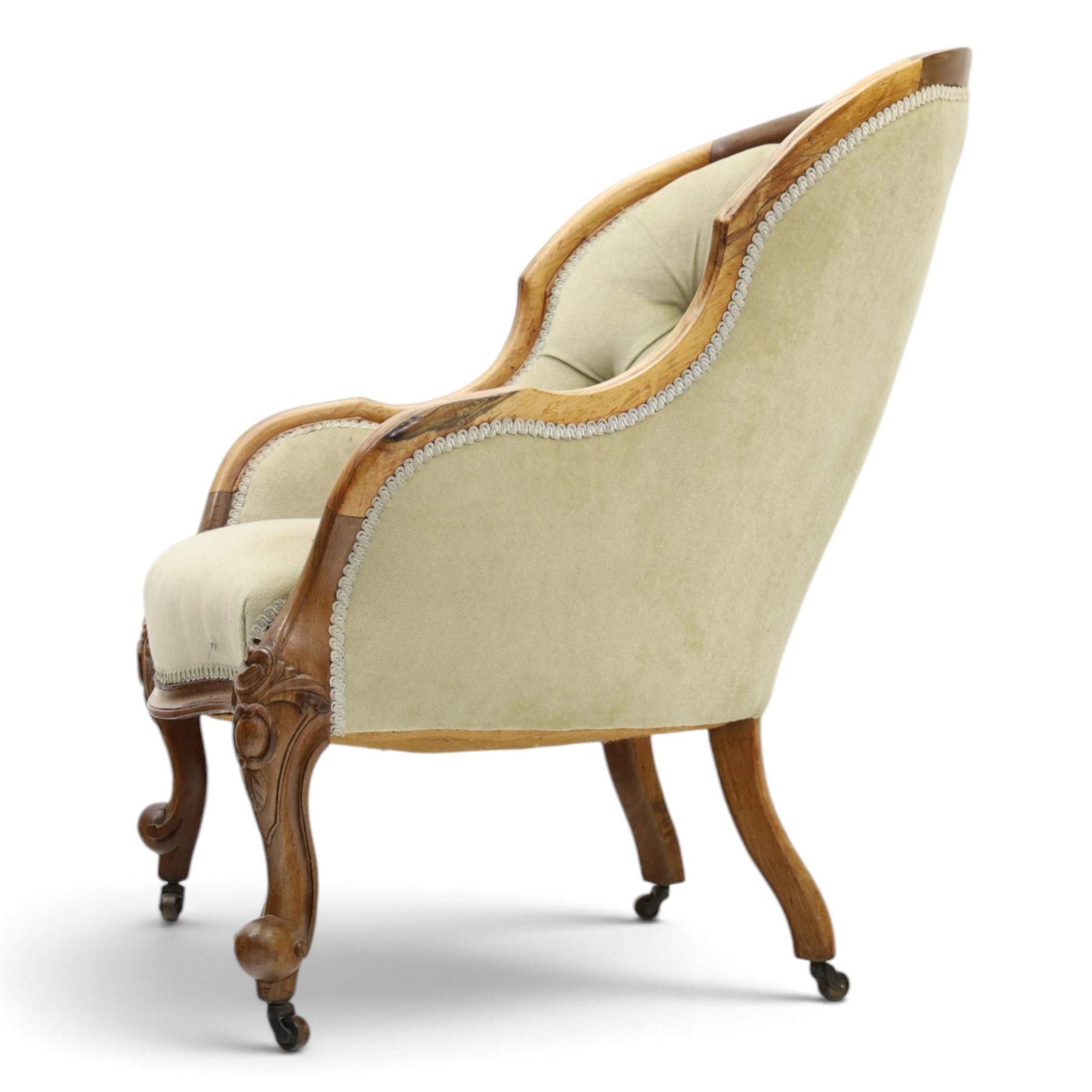Victorian carved walnut framed armchair with matching stool, the tub-shaped chair with moulded and shaped frame and arm terminals, raised on scrolled cartouche carved supports with scroll feet and castors, buttoned back and sprung seat upholstered in sage green fabric; the small circular footstool with buttoned seat and scroll supports (W36cm H15cm)