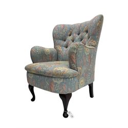 Mid-20th century wingback armchair, upholstered in soft blue floral patterned fabric with button-tufted backrest and curved arms and raised on cabriole supports