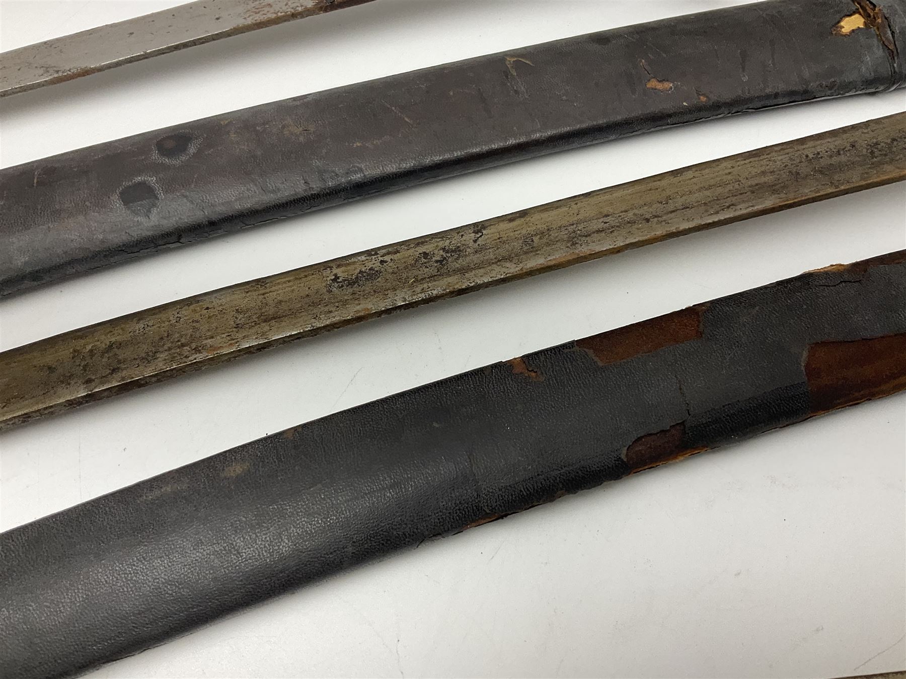 Four Indian tulwar swords; three with cast brass hilts and one with iron hilt; longest blade 81cm; all with scabbards (4)