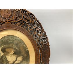 Pair of early 20th century carved and pierced Burmese hardwood frames, each of oval form carved with shaped panels, the uppermost detailed with initials, joined by flowering vines interspersed with birds, containing two coloured prints after George Morland 'Delia in Town', and 'Delia in the Country', overall H45cm W36.5cm apertures H27.5cm W22cm