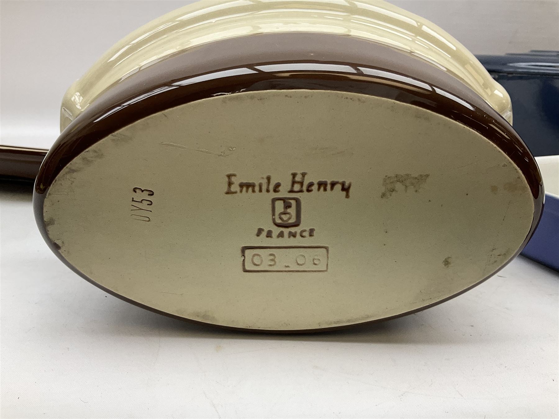 Emile Henry covered casserole dish of oval form in two tone brown and cream, no. 03.06, together with cast iron Nomar twin handled lidded casserole dish of oval form in navy, and other ovenware including Flintware ICTC, largest L35cm