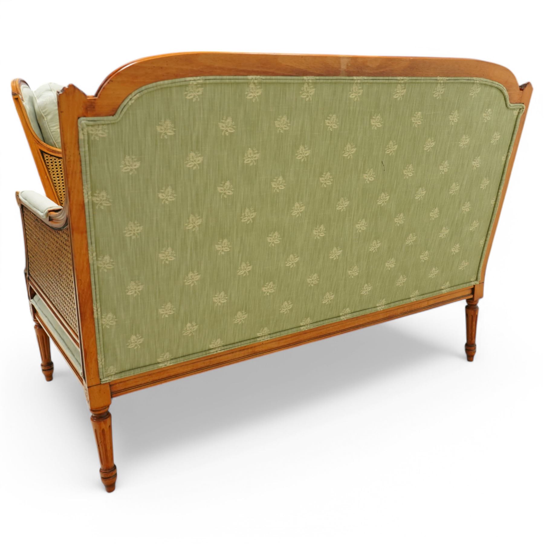 French Empire design varnished wood three piece lounge suite comprising of two cane armchairs and matching sofa, carved top rails with foliate terminals, cane side panels and padded scroll arms, upholstered in a green brocade with matching piping, on fluted legs
