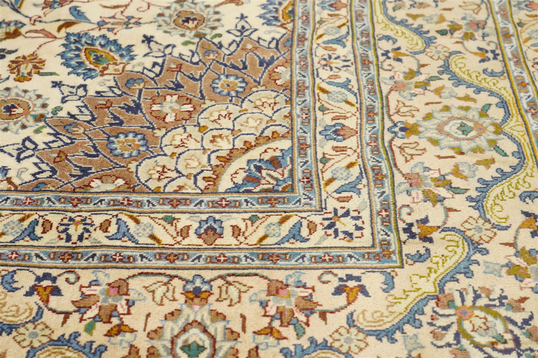 Central Persian Nain hand-knotted carpet, ivory field with central radiating medallion with pendants, issuing an all-over design of scrolling vines, palmettes, and floral sprays within confirming spandrels, framed a complimentary foliate border flanked by multiple guard stripes, with cotton fringe ends 