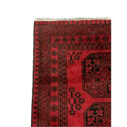 Afghan Bokhara rug, red ground and decorated with three Gul motifs, geometric design borders decorated with flower heads