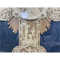 Cork carving of a religious cross depicting intricate scenes of various religious figures and motifs amongst trees and foliage, with central circular panel of Jesus Christ, in glazed frame, H95cm