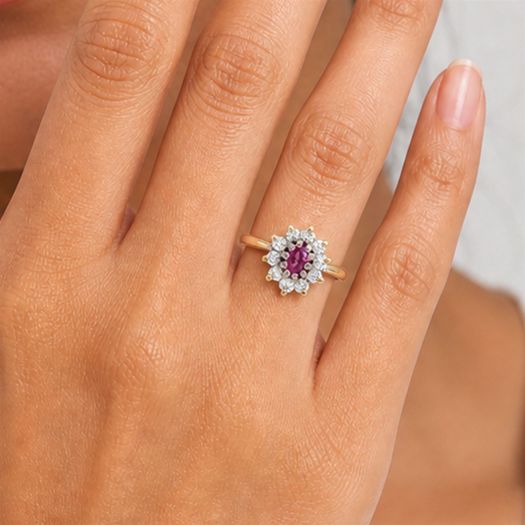 18ct gold pink sapphire and diamond cluster ring, single oval cut sapphire of 0.23 carat, surrounded by ten round brilliant cut diamonds, Birmingham 1985, total diamond weight 0.26 carat