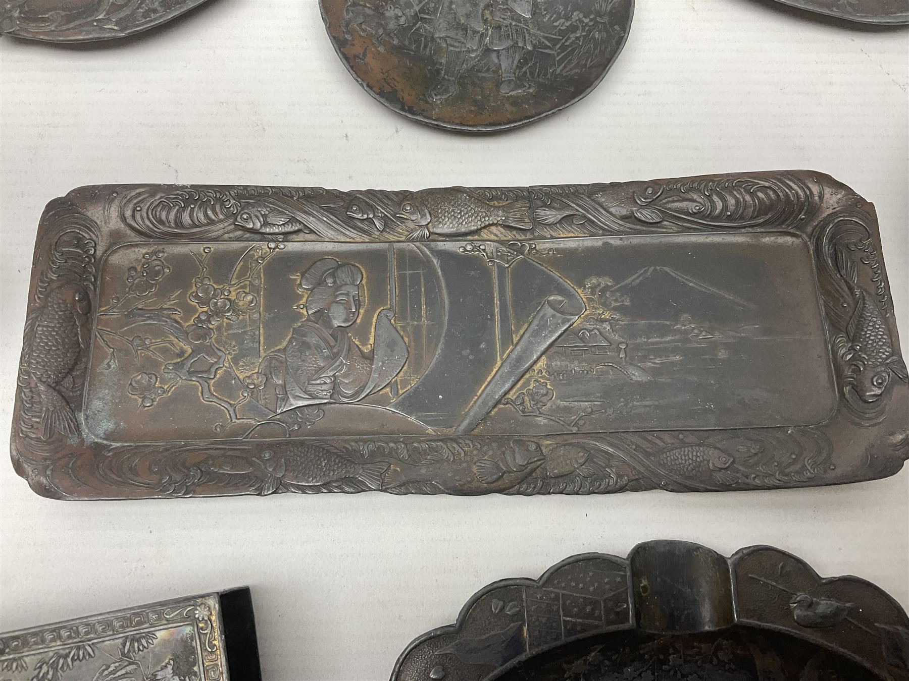 Brass sunfish ashtray, Chinese silver plated trinket box with mirror, bronzed matchbox cover and a collection of other Oriental bronzed embossed metal trays