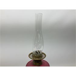 Victorian table standing oil lamp, brass fittings, cranberry glass reservoir, brass column on black enamelled ceramic base, with a frosted glass shade and clear glass chimney, H68cm