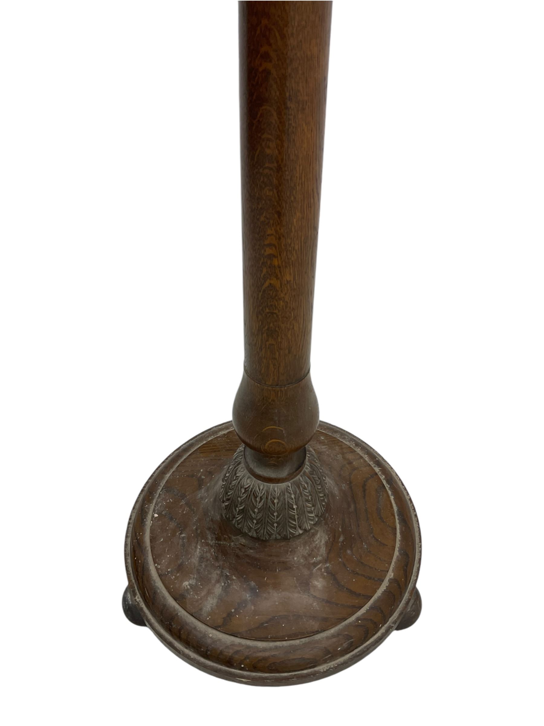 Early 20th century oak standard lamp base, of baluster form with fluted acorn finial and carved foliate decoration to the base, raised on circular plinth with bun feet