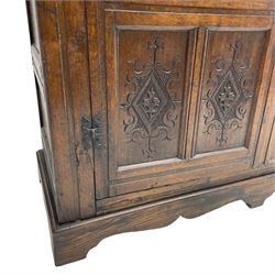 Large 18th century and later oak livery cupboard, projecting moulded and dentil cornice, sunken fillet moulded frame, triple vertical panelled central upright, enclosed by two doors each with five panels, the top row of panels carved with stylised scrolls, the lower panels carved with foliate lozenges, on shaped bracketed skirt base 