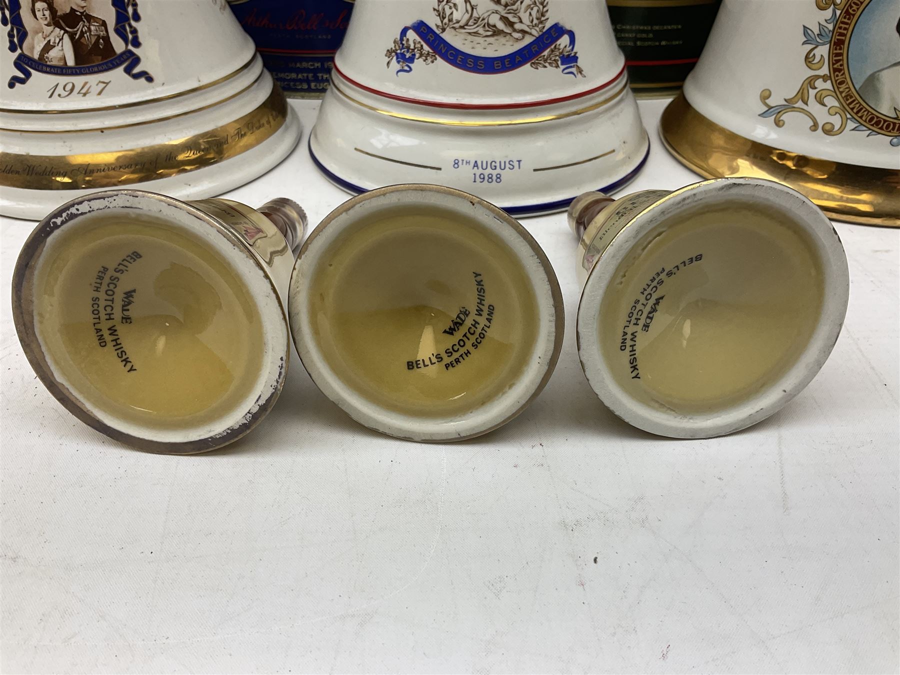 Bells, Scotch whisky, in seven Wade ceramic decanters, comprising two Christmas decanters 1990 and 1991, 60th birthday of Queen Elizabeth II decanter, Golden Wedding anniversary of the Queen and the Duke of Edinburgh decanter, Birth of Princess Beatrice decanter, Birth of Princess Eugenie decanter and Queen's mothers, together with Bells, blended Scotch whiskies, three miniatures in Wade ceramic decanters, various contents and proofs