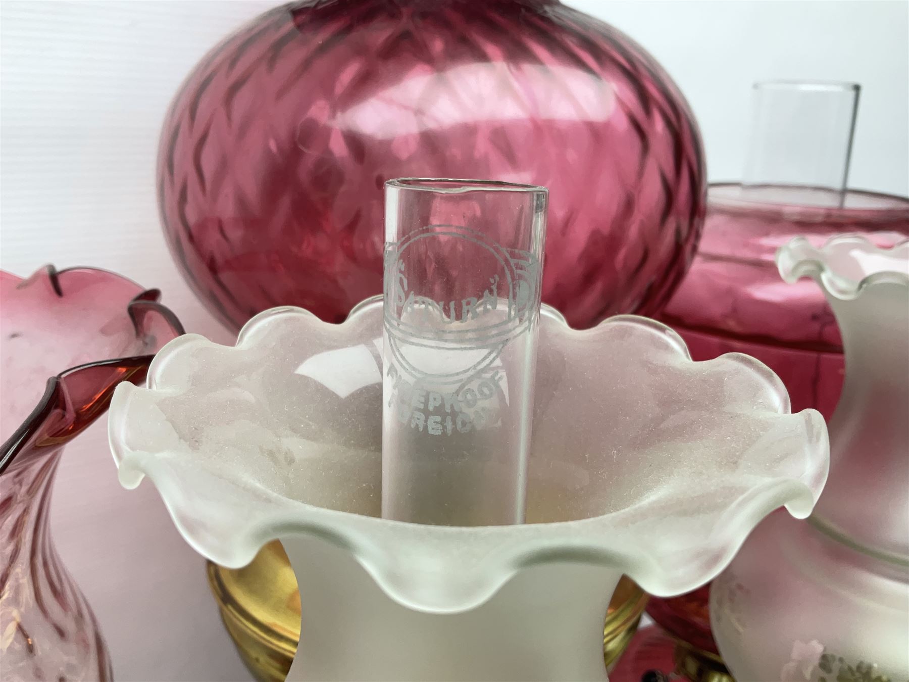 Victorian cast brass oil lamp, with fluted pink glass shade, together with two smaller brass oil lamps with pink shades and reservoirs and a pair of oil lamps, the bases modelled as putti, with pink glass reservoir  and frosted shades, tallest H70cm