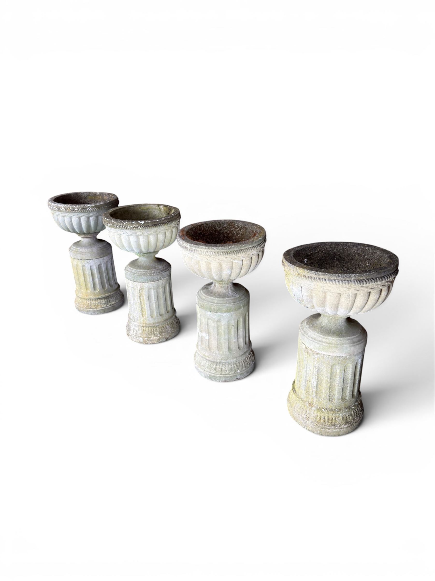 Four 20th century good quality weathered cast stone pedestal urns, circular lobed bowls with rope twist and lattice border, raised on squat base with fluted columns