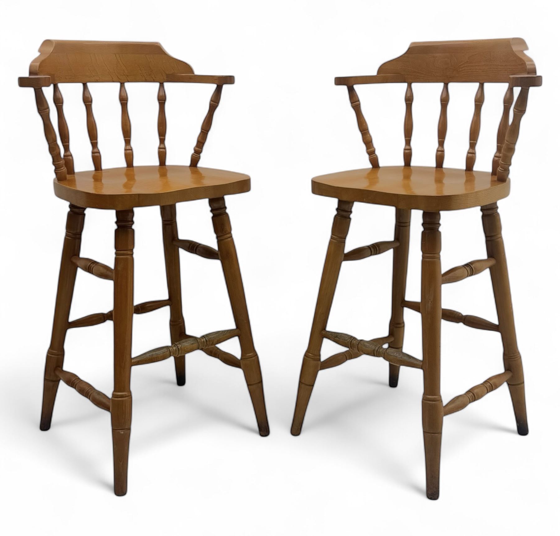 Pair of late 20th century beech bar stools, with curved top rail and turned spindle back, shaped seat over four turned legs united by multiple stretchers