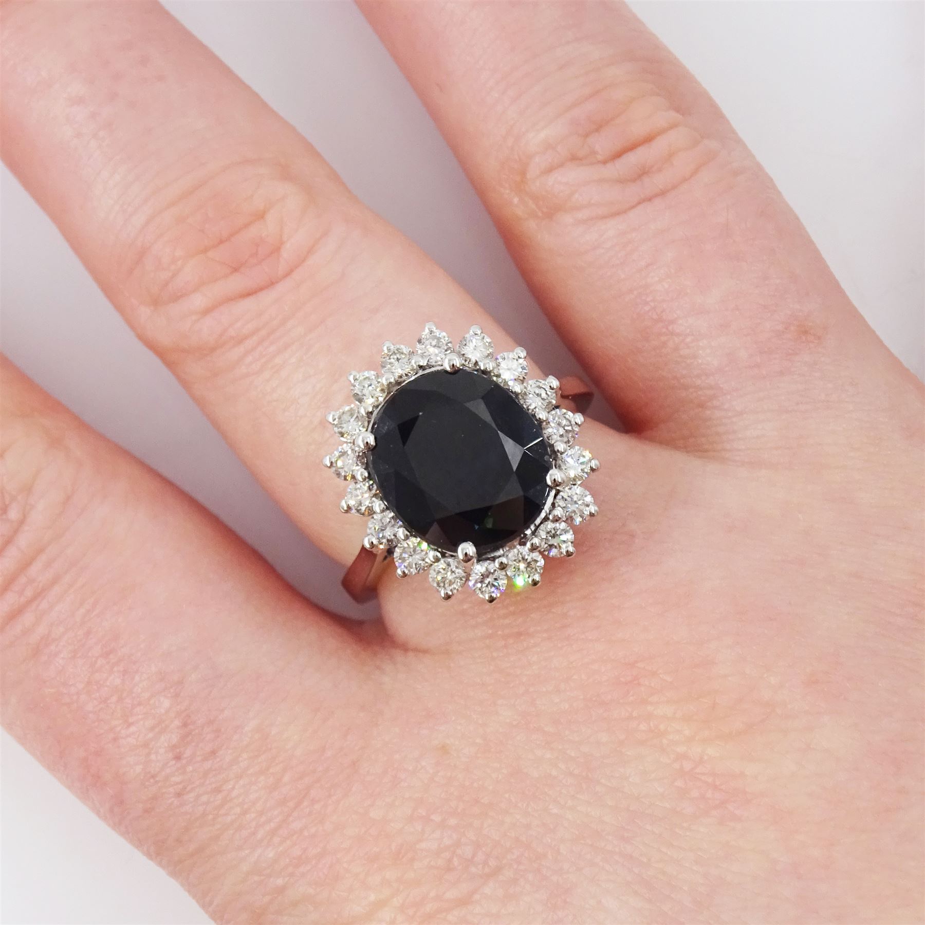 18ct white gold sapphire and diamond cluster ring, single oval cut sapphire of approx 4.30 carat, sounded by eighteen round brilliant cut diamonds, stamped, total diamond weight approx 0.75 carat