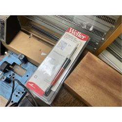 Six shelved cabinets for displaying ‘00’ gauge locomotives comprising plain plywood and white painted examples with track applied to various shelves, largest H63cm, W107cm, D27cm; Collection of tools for building model locomotives to include Weller PU-2D Soldering Pencil and Standard Tip Soldering Iron 20W/230V, Humbrol Modellers Airbrush, Power Supply Units and two wooden chests one of which housing a collection of tools including tweezers, scalping tools, wrenches etc 