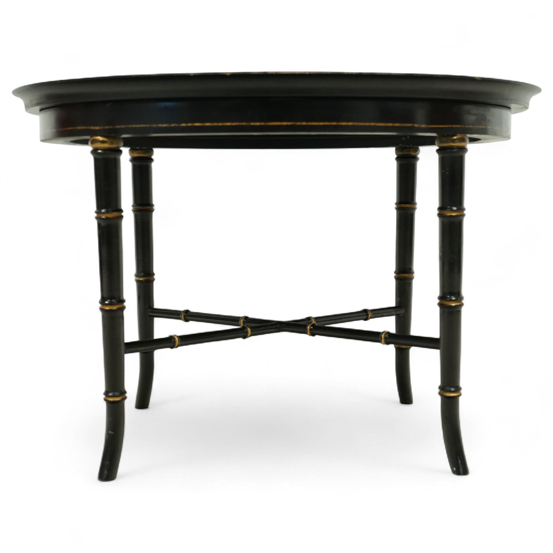 Regency style oval toleware tray table, the black lacquered top with gilt floral decoration, on ebonised faux bamboo frame with stretcher supports