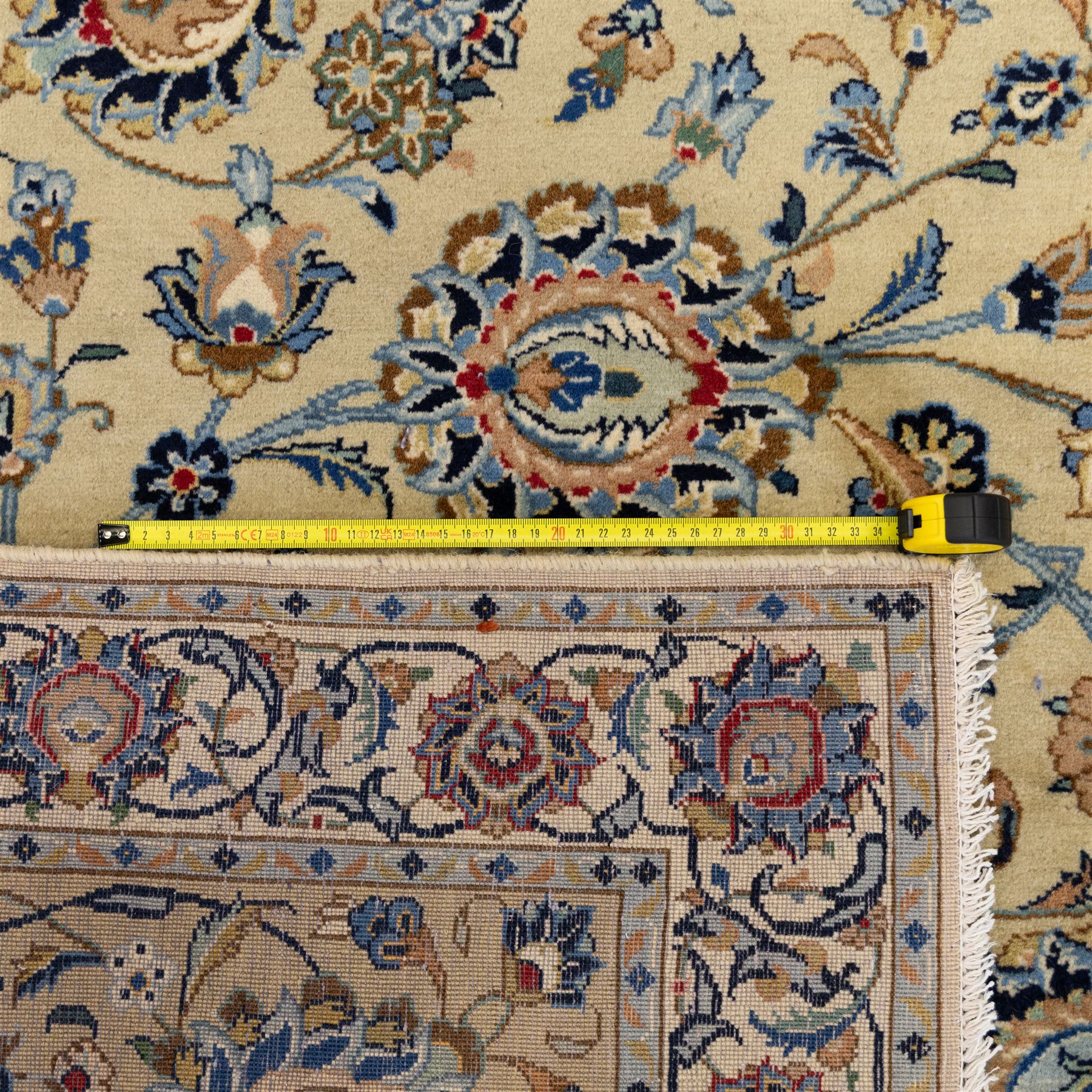Persian Kashan carpet, beige ground, field with an all-over design of scrolling palmettes and floral sprays in blue and terracotta within a ivory ground and pale blue floral border