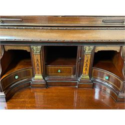 Large and impressive late 19th century Irish mahogany secretaire bookcase, moulded sloped arch dentil pediment decorated with central carved mask surrounded by linen festoons and trailing bellflowers, canted and fluted uprights with carved acanthus leaf upper and lower brackets, enclosed by two astragal glazed doors in the form of trophies with twist ribbon carved mouldings, inlaid with fanned spandrels and trailing leaf painted satinwood band, cylinder roll top inlaid with central fan motif and fanned spandrels, pull-out action revealing stepped fitted interior, central tambour roll cupboard flanked by two Composite pilasters and a combination of drawers and pigeon holes, fitted with three break-front drawers, matched canted and fluted corners with acanthus leaf carvings, on square tapering and fluted spade feet