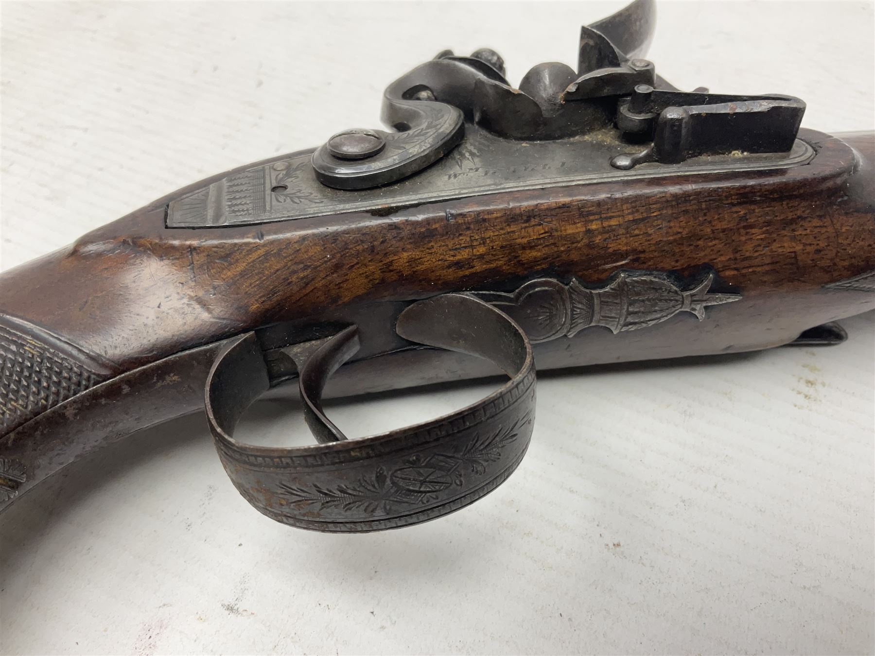 Early 19th century Wm. Hollis flintlock belt or pocket pistol, approximately 20 bore, the 10cm barrel with ram rod under, engraved lock plate with maker's name and roller frizzen, engraved trigger guard with pineapple finial and walnut stock with chequered grip L25cm overall