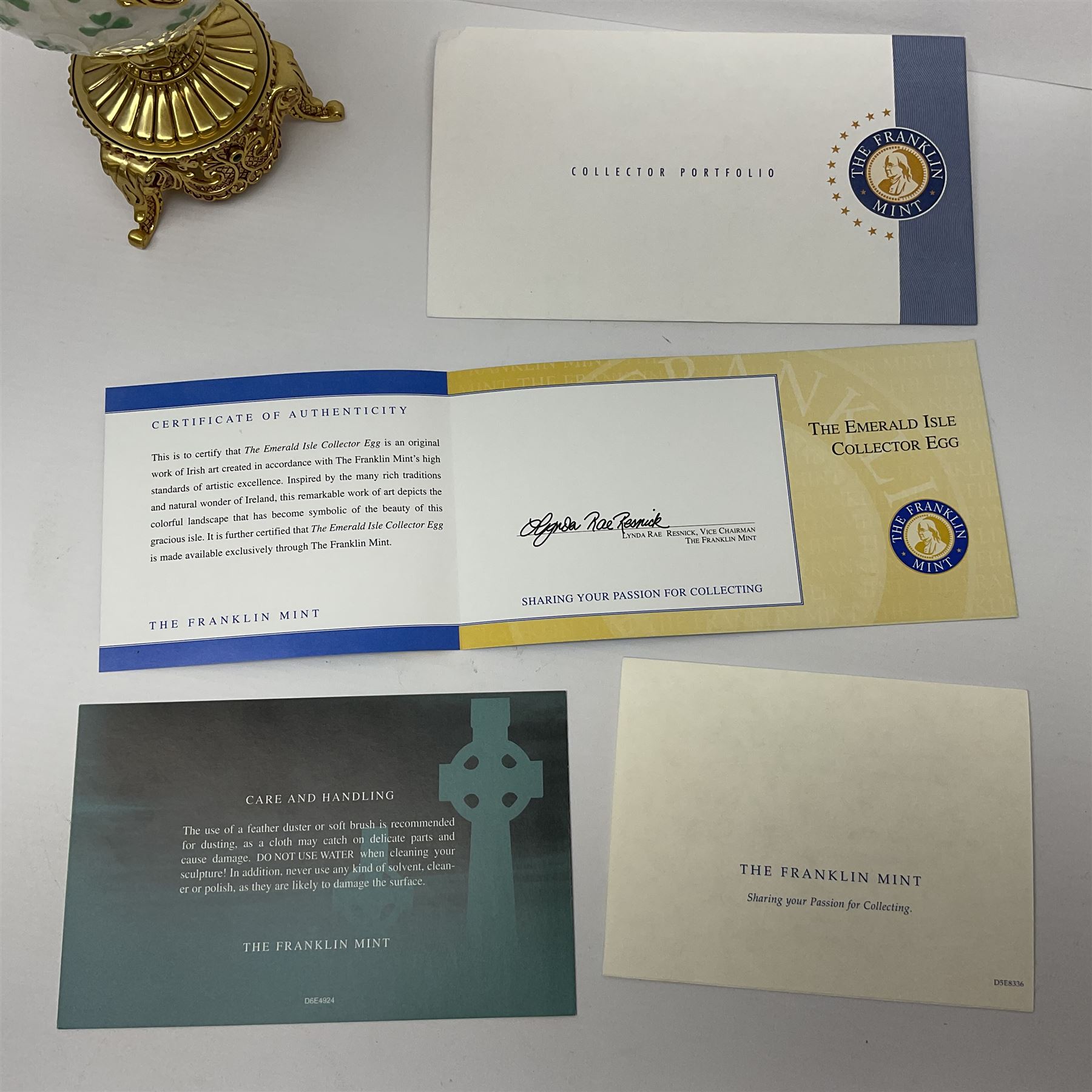 Franklin Mint The Emerald Isle Collector Egg, the egg decorated with embossed shamrocks upon a cream ground, with a gilded shamrock finial, accents and openwork door, opening to reveal a miniature landscape scene, upon three gilded feet set with green paste stones, with certificate of authenticity H23cm, 