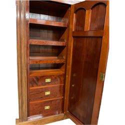 Victorian mahogany triple wardrobe, the pediment relief carved with urn and linen swags, the central panelled door carved with two fan motifs enclosing slides and drawers, two mirror glazed doors with bevelled plates enclosing hangings space and drawers, plinth base